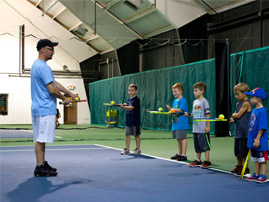 Instructor helping junior tennis players